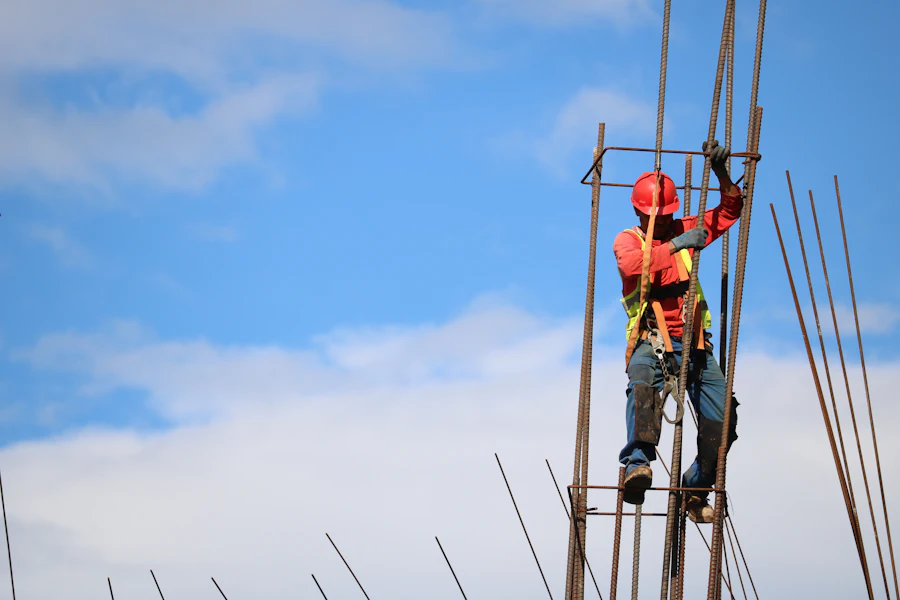 Ironworker in a harness climbing rebar against the sky