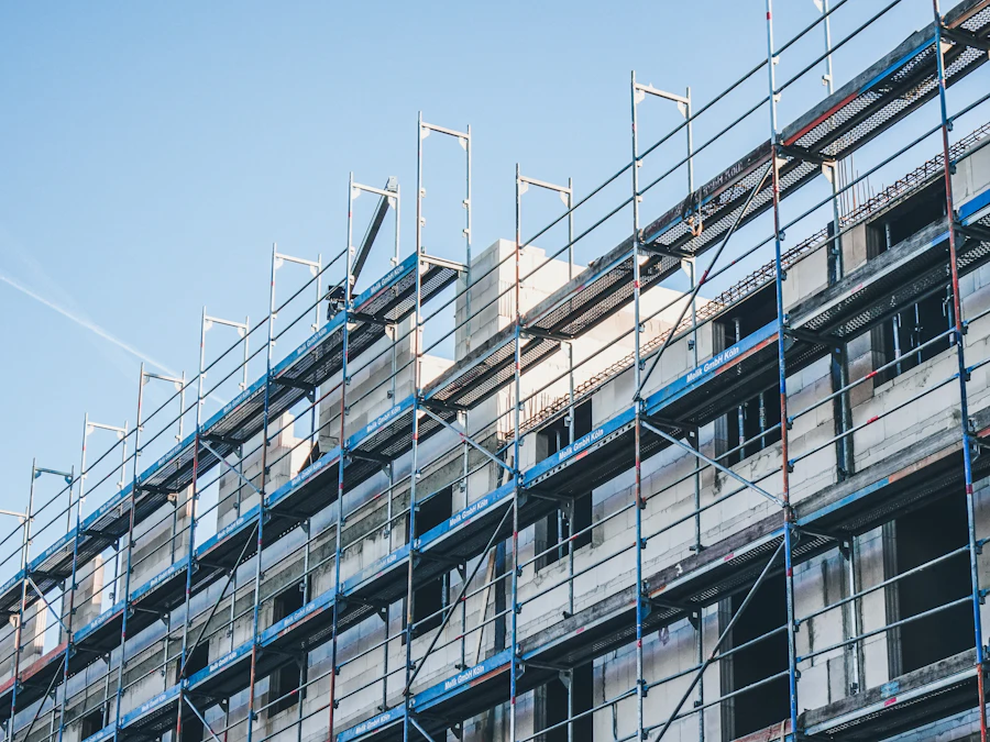 Apartment building wrapped in blue scaffolding against a clear sky
