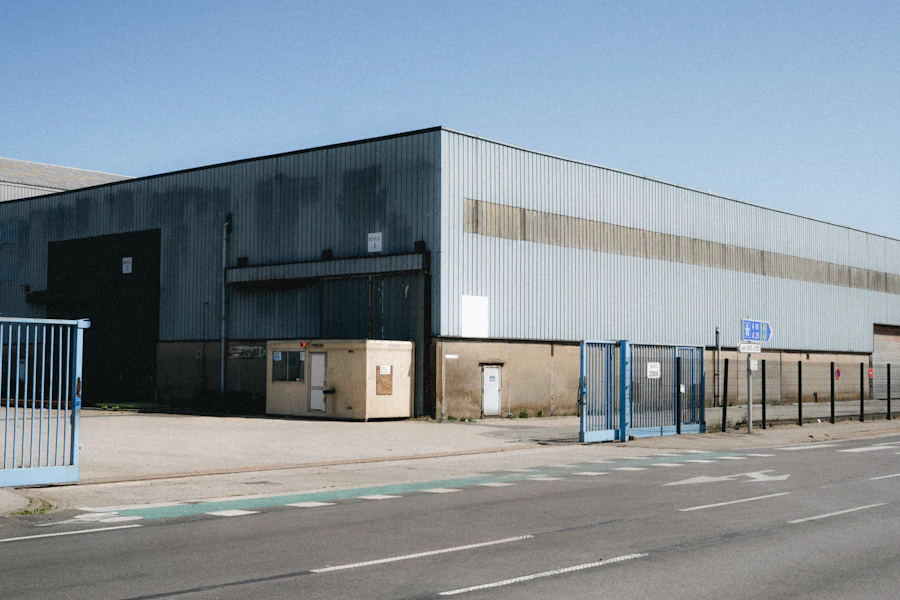 Long dark-clad distribution warehouse with a fenced truck court