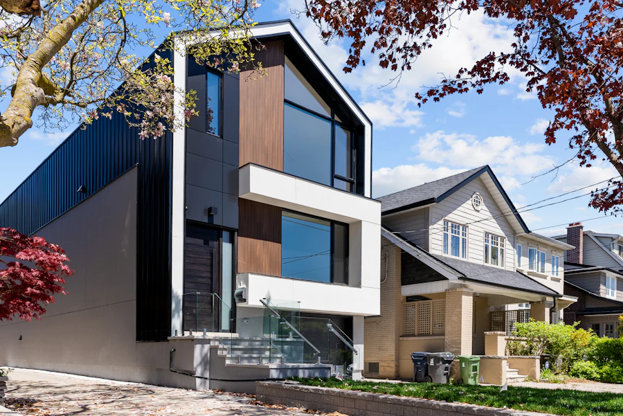 Modern three-storey house clad in dark timber and white render on a leafy street