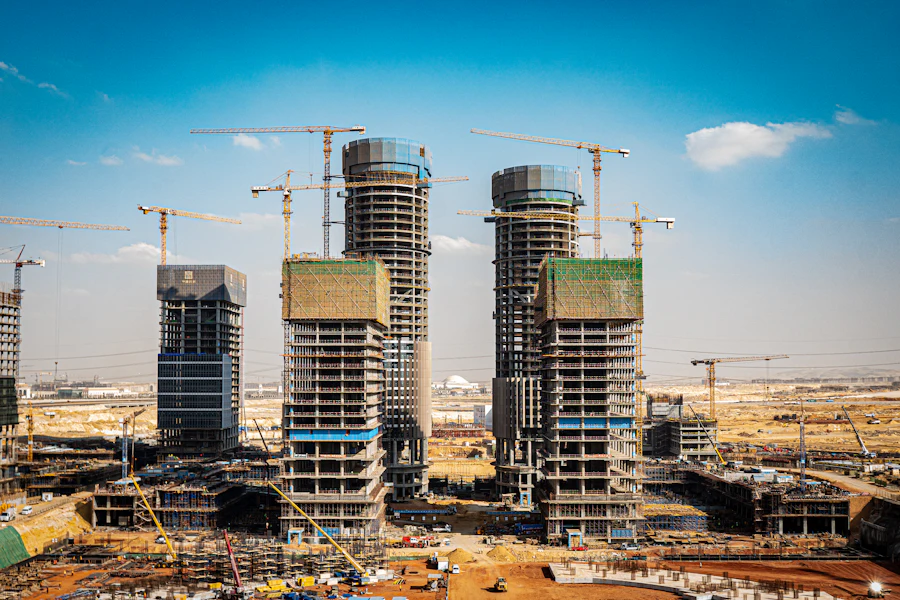 Twin residential towers rising under tower cranes on a desert-edge site