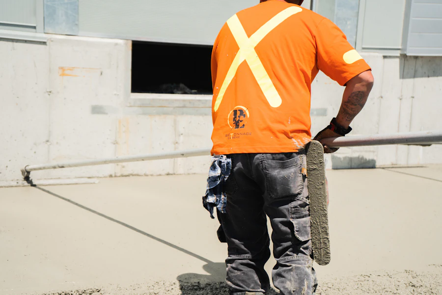 Worker in a high-visibility vest guiding a concrete hose on a slab